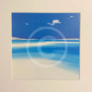 Mounted artwork of a beach scene with blue sky and white clouds.