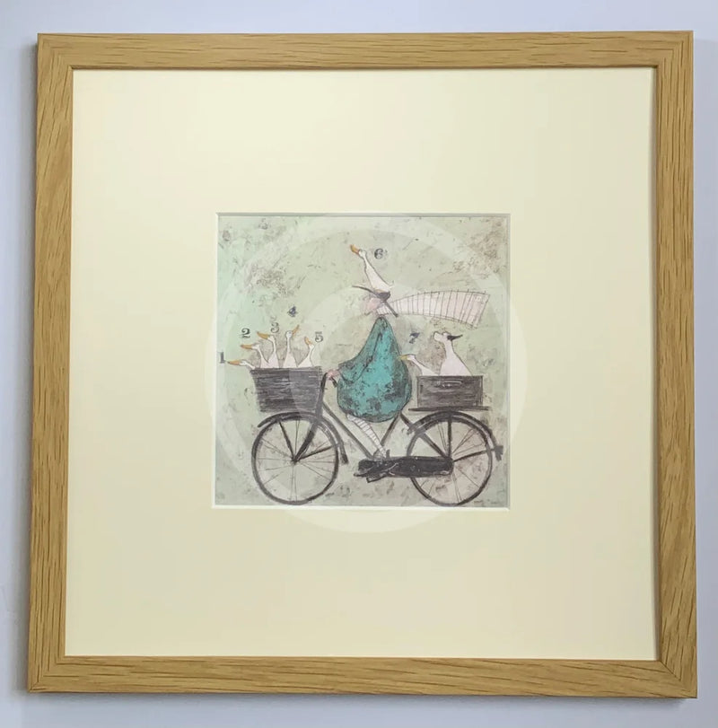 Meet the Mustards: All Aboard the Ducky Express by Sam Toft, mounted miniature print. A fun pictures of a man on a bicycle with two baskets carrying several white ducks and his black and white dog. Framed in oak.