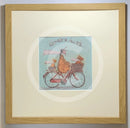 Meet the Mustards: Ginger Nuts by Sam Toft, mounted miniature print. A fun print of a man riding his bicycle with a ginger coloured dog riding in the basket at the front and a striped ginger cat riding on the back. Framed in oak.