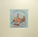 Meet the Mustards: Ginger Nuts by Sam Toft, mounted miniature print. A fun print of a man riding his bicycle with a ginger coloured dog riding in the basket at the front and a striped ginger cat riding on the back. 