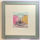 Meet the Mustards: Out For a Bit of Brunch by Sam Toft, mounted miniature print. A man rides on a bicycle with his dog sat in the front basket, they have a picnic basket on the back. They are riding past two pink and yellow beach huts. Framed in Nordic Blue. 