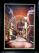 Framed artwork of a snowy street scene with buildings and a cathedral in the background.