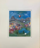 Mounted artwork of a colourful village scene with balloons against a mountainous background.