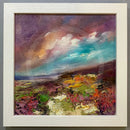 Framed painting of a landscape with colorful sky and earth tones.