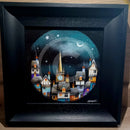 Framed artwork of a night scene with a village and starry sky.